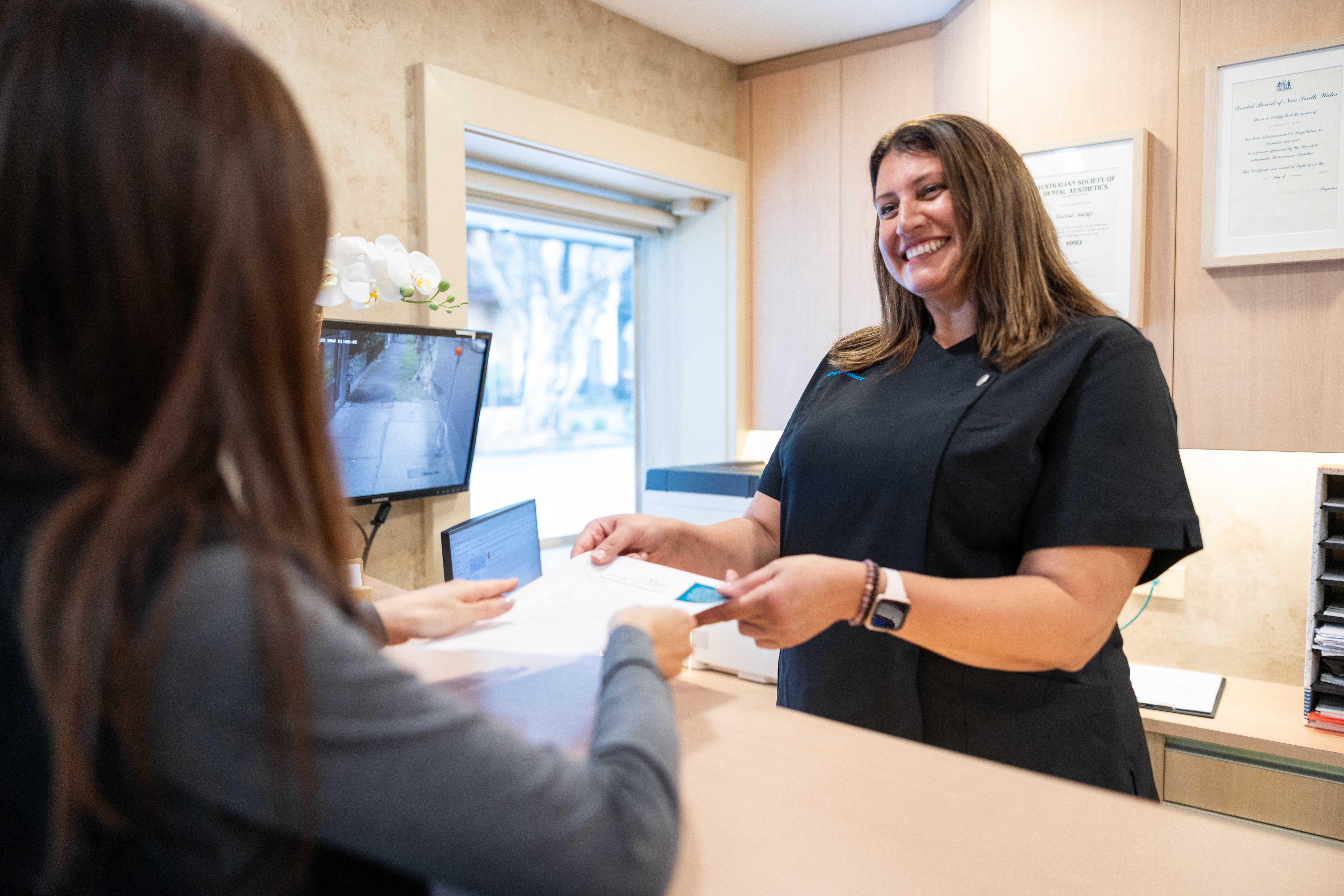 Maria, Practice Manager, greeting a patient at reception